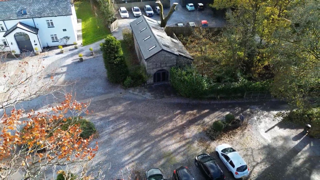 Aerial view across a courtyard, outbuildings and parking area