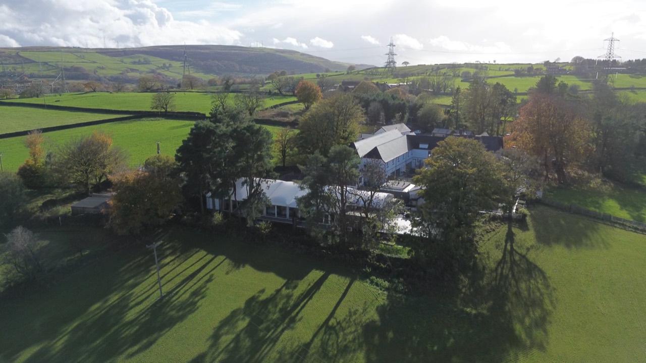 Wide aerial view of rural premises, fields and the surrounding hills